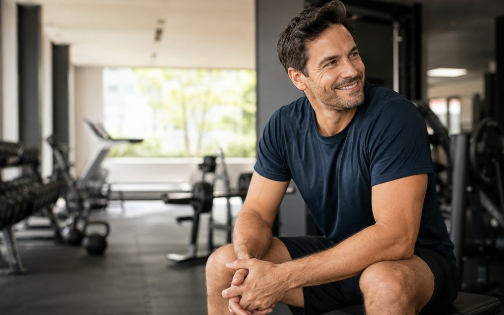 A fit middle-aged man sitting in a gym