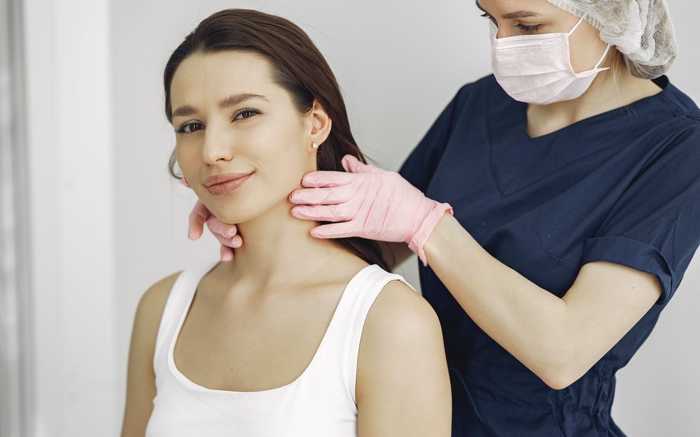 A clinician examining a patient's thyroid gland at the neck